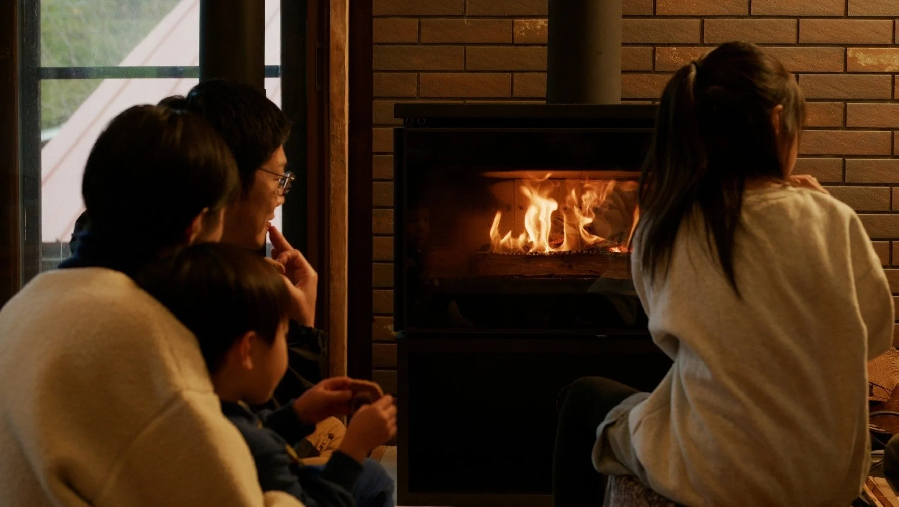 暖炉の燃える火を囲んで家族がくつろいでいる様子です