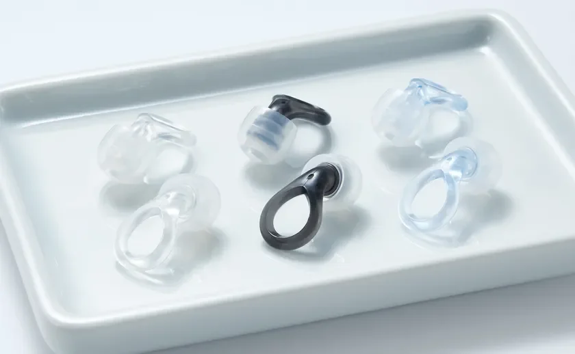 白いトレイの上に、透明、黒、水色の複数のデザインの耳栓が並べられています