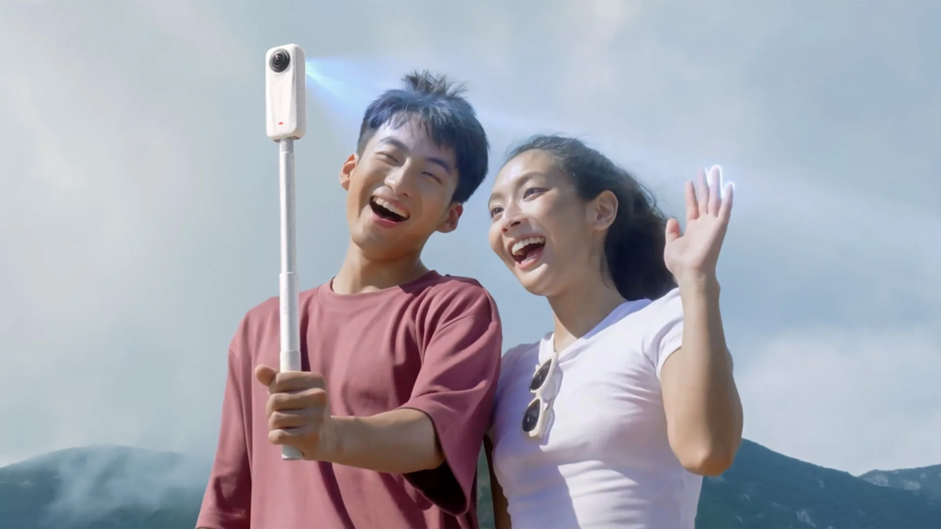 屋外で360度カメラを使って自撮りを楽しむカップル