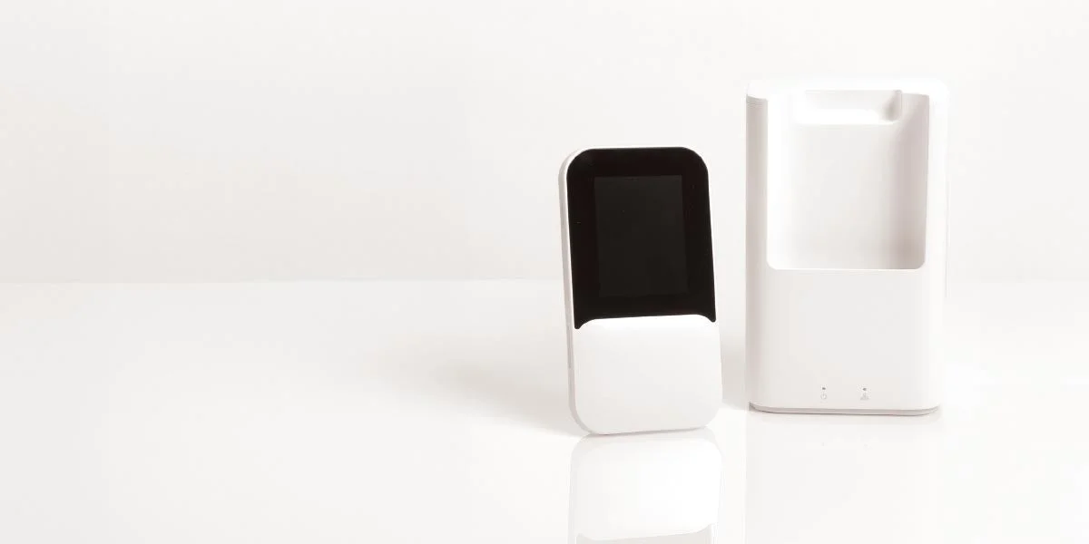 白い背景に、黒い画面を持つ白い電子機器と、それに対応する充電ドックが並べられています