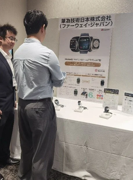 華為技術日本株式会社（ファーウェイ・ジャパン）のブースで、男性がHUAWEI WATCH Dなどのウェアラブル製品の展示を熱心に見ている様子