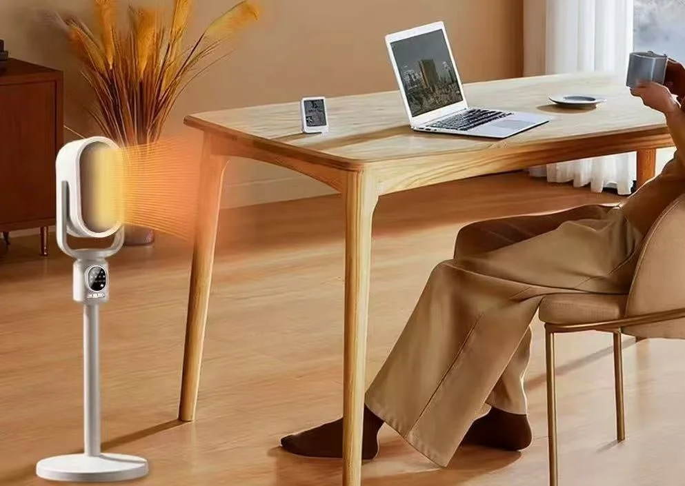 自宅のリビングで、木製のテーブルに向かいノートパソコンを使用している人物が、足元に設置されたファンヒーターで暖をとっている様子。快適な在宅勤務やリラックスタイムを表現しています。