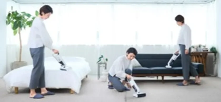 部屋でコードレス掃除機を使って掃除をする人の様子