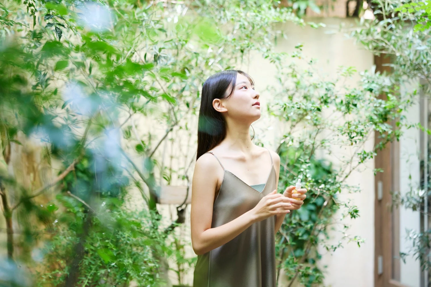 女性が自然の中で美容液のボトルを持つ