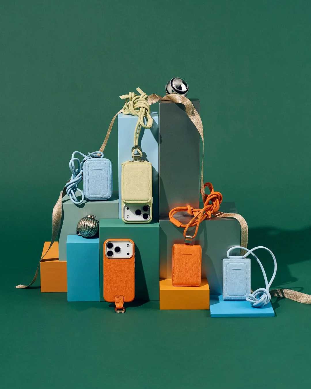 カラフルなブロックに並ぶストラップ付きスマホケースとカードホルダー