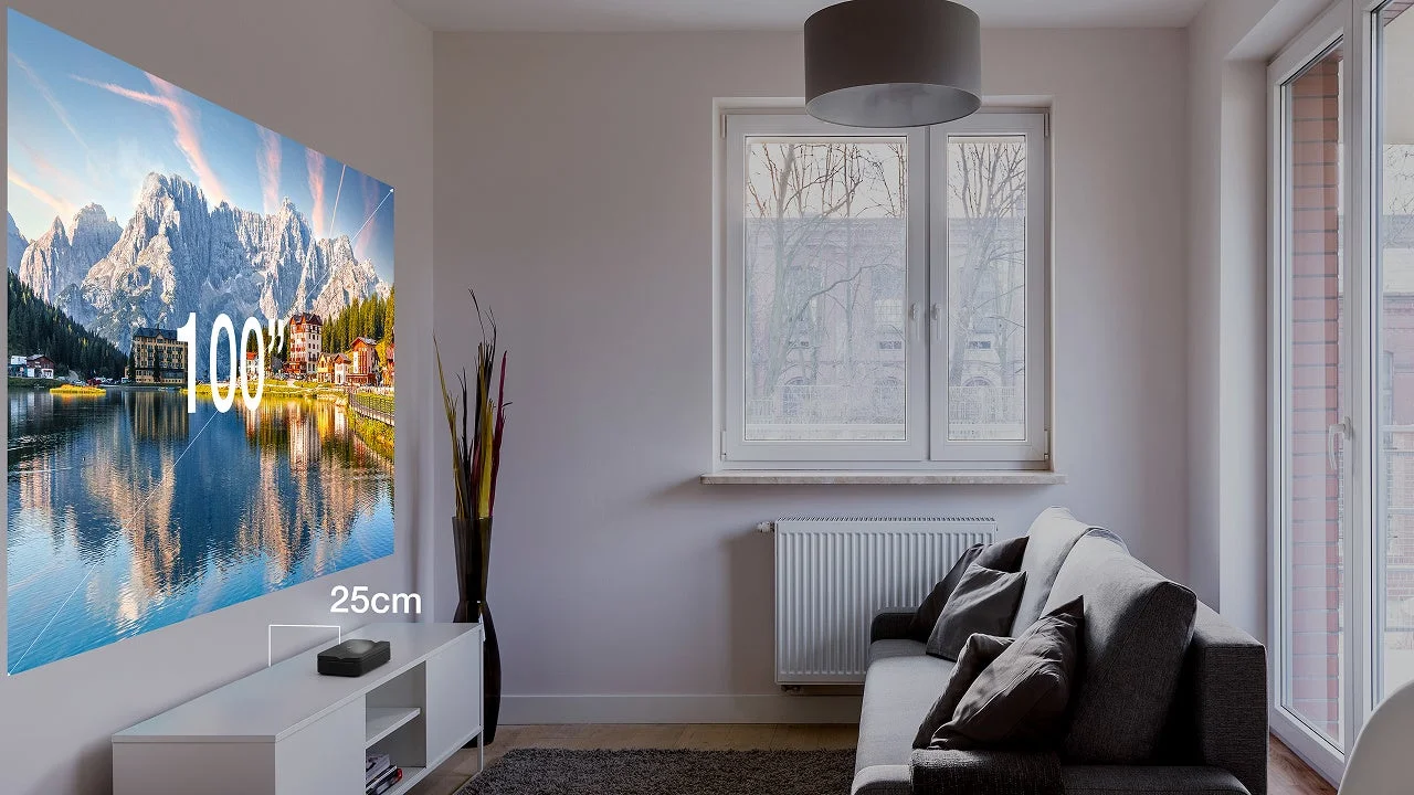 リビングルームで超短焦点プロジェクターが壁に100インチの美しい湖と山々の景色を投影