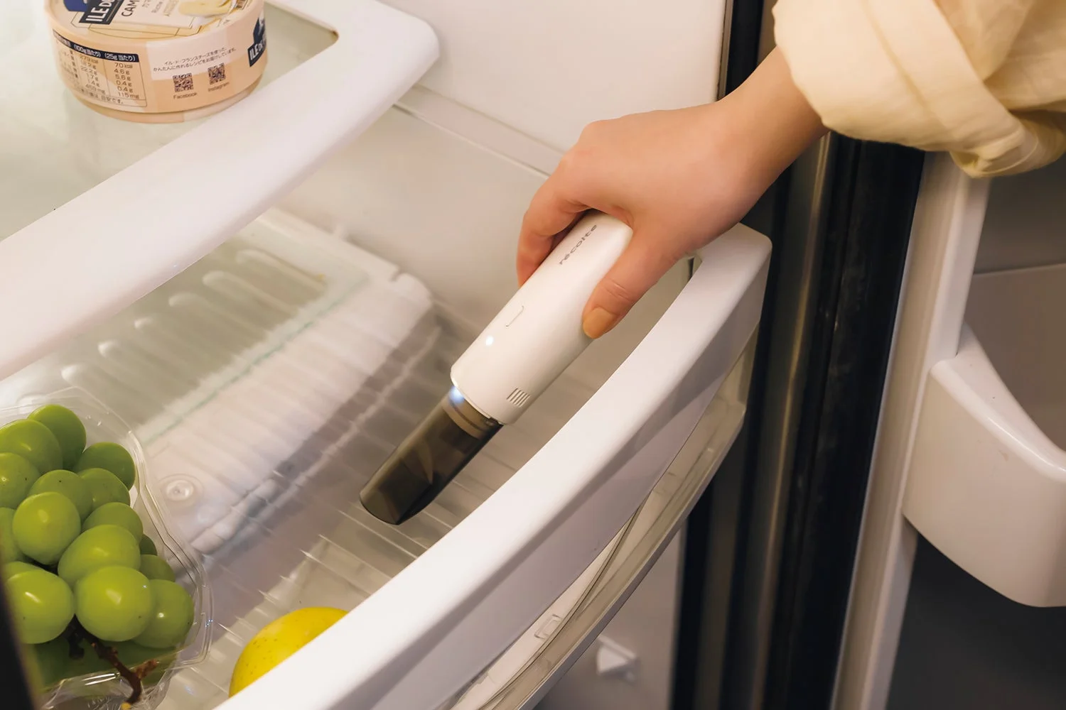 レコルト コードレス スポットクリーナーで冷蔵庫の棚を掃除する様子