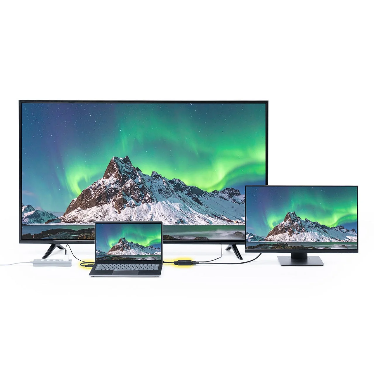ノートパソコンが2台の外部モニターに接続され、全ての画面にオーロラと雪山が表示されている様子