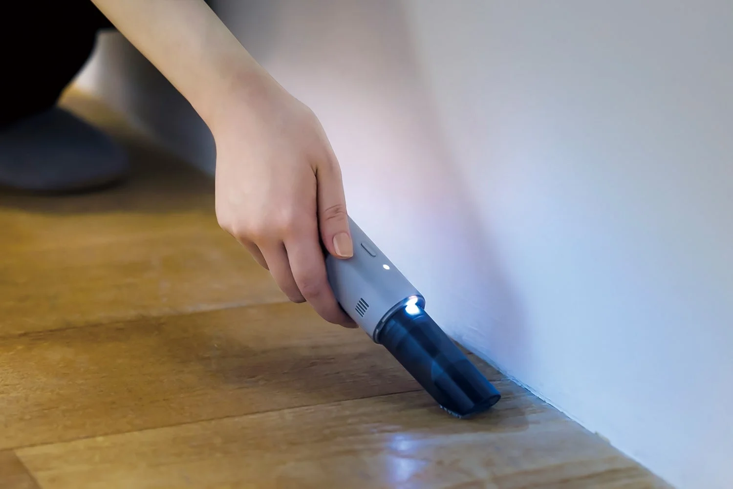 レコルト コードレス スポットクリーナーのライトで床の隅を照らしながら掃除する様子