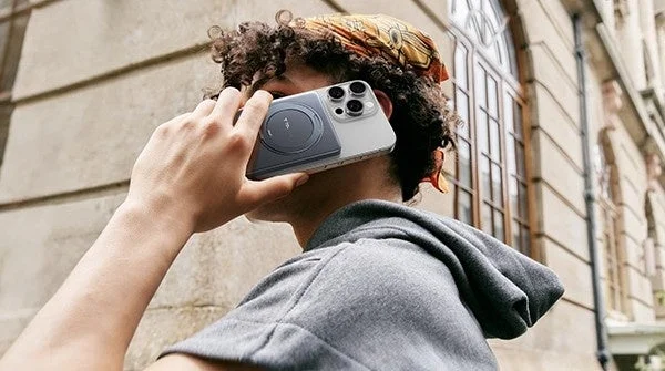 MagSafe対応のモバイルバッテリーが装着されたスマートフォンを耳元に当てている人物