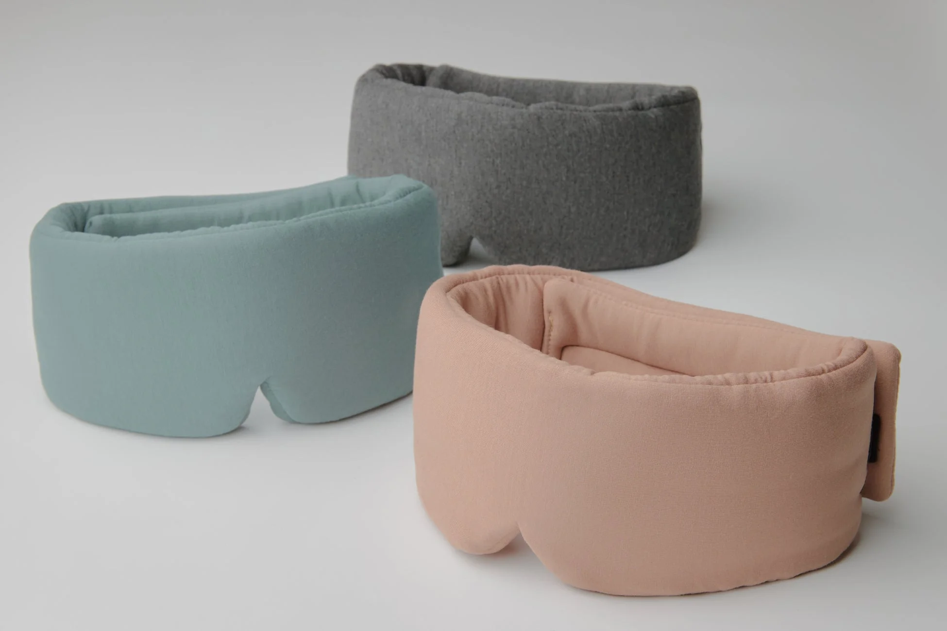 白背景にミントグリーン、グレー、ピーチピンクの3色のソフトなアイマスクが並べられています。