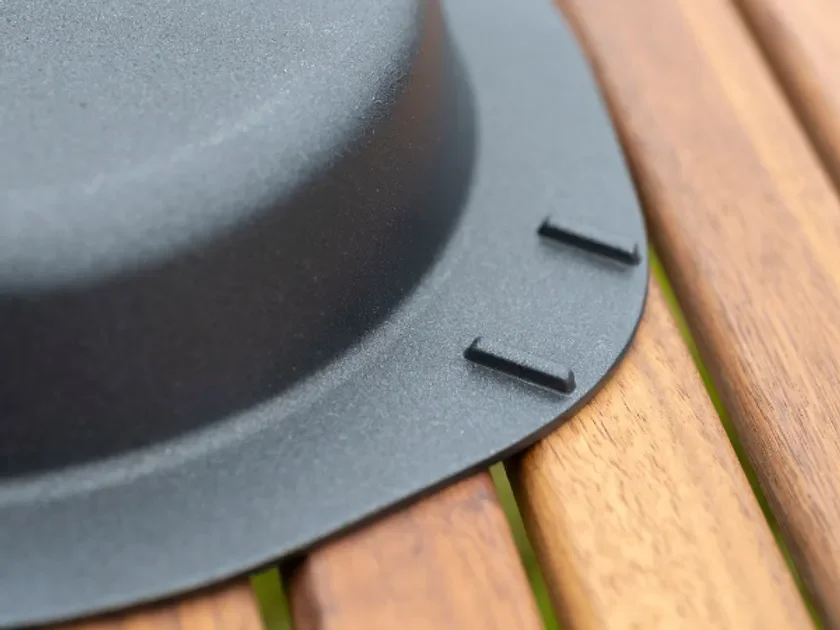 黒い金属製の調理器具の側面が、木製のテーブルの板の上に置かれているクローズアップ写真