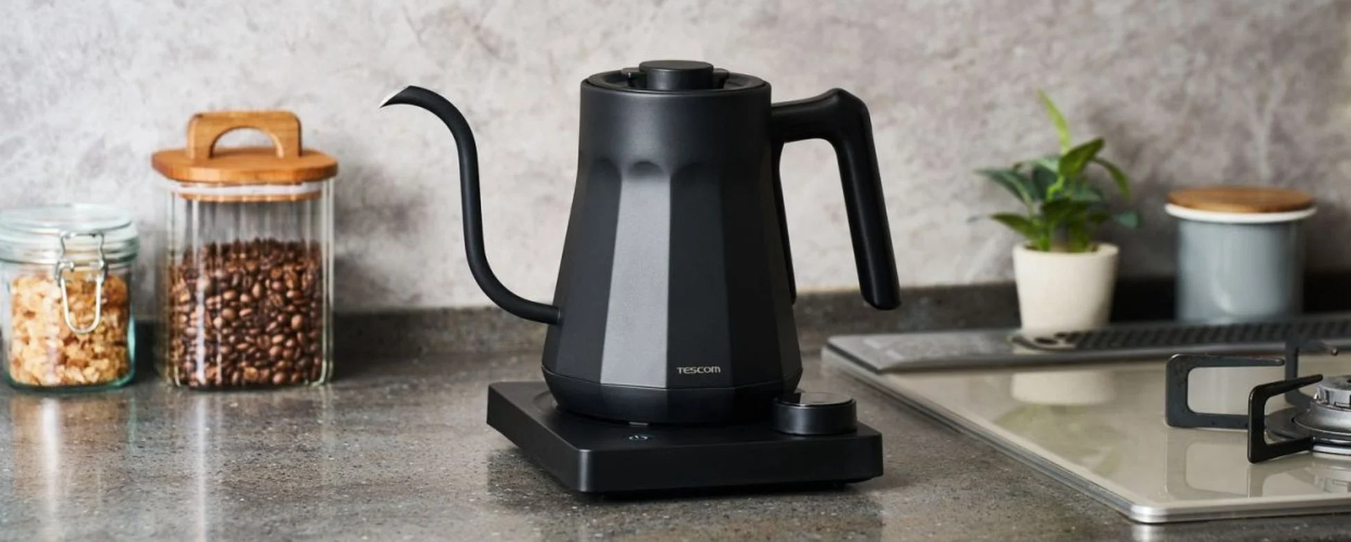 モダンなデザインの黒い電気ドリップケトルが、コーヒー豆などの保存容器とともにキッチンカウンターに置かれています。