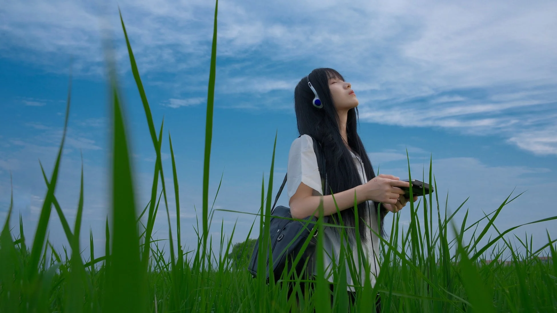 草原でヘッドホンをする女性