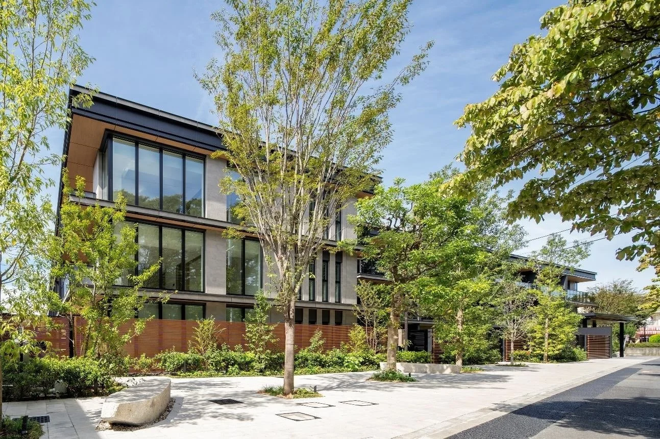 青空の下、緑豊かな植栽に囲まれたモダンな集合住宅の外観