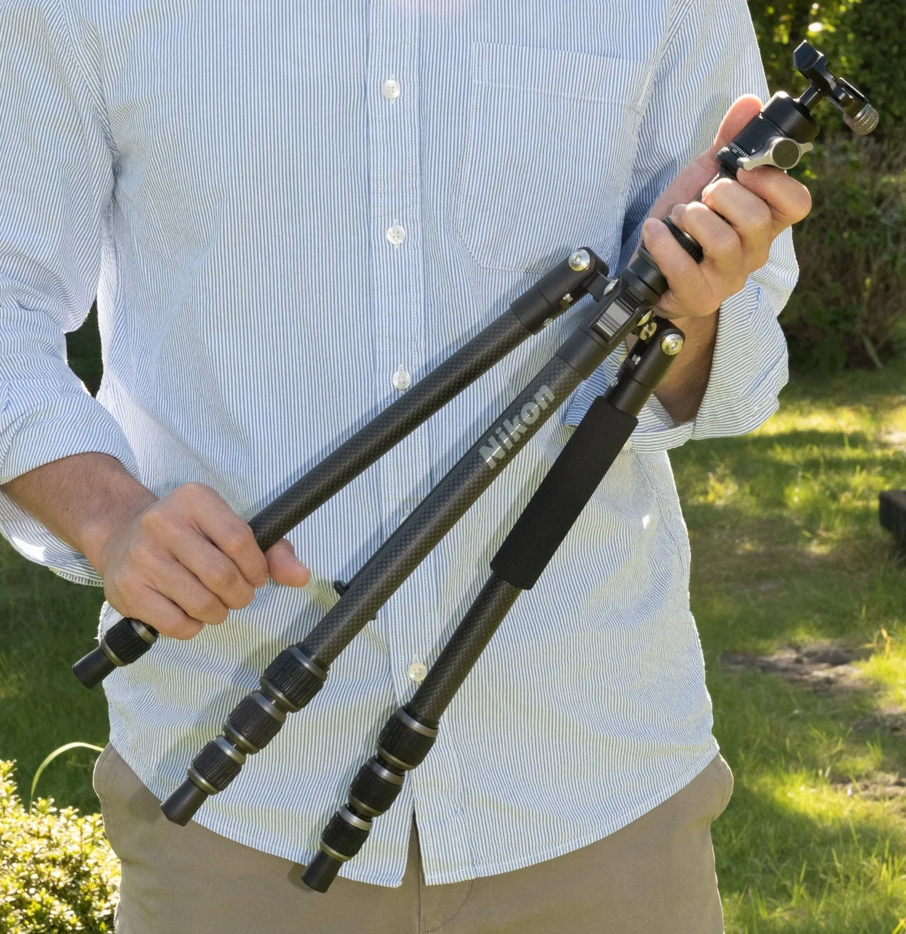 男性が屋外で三脚を持っている様子