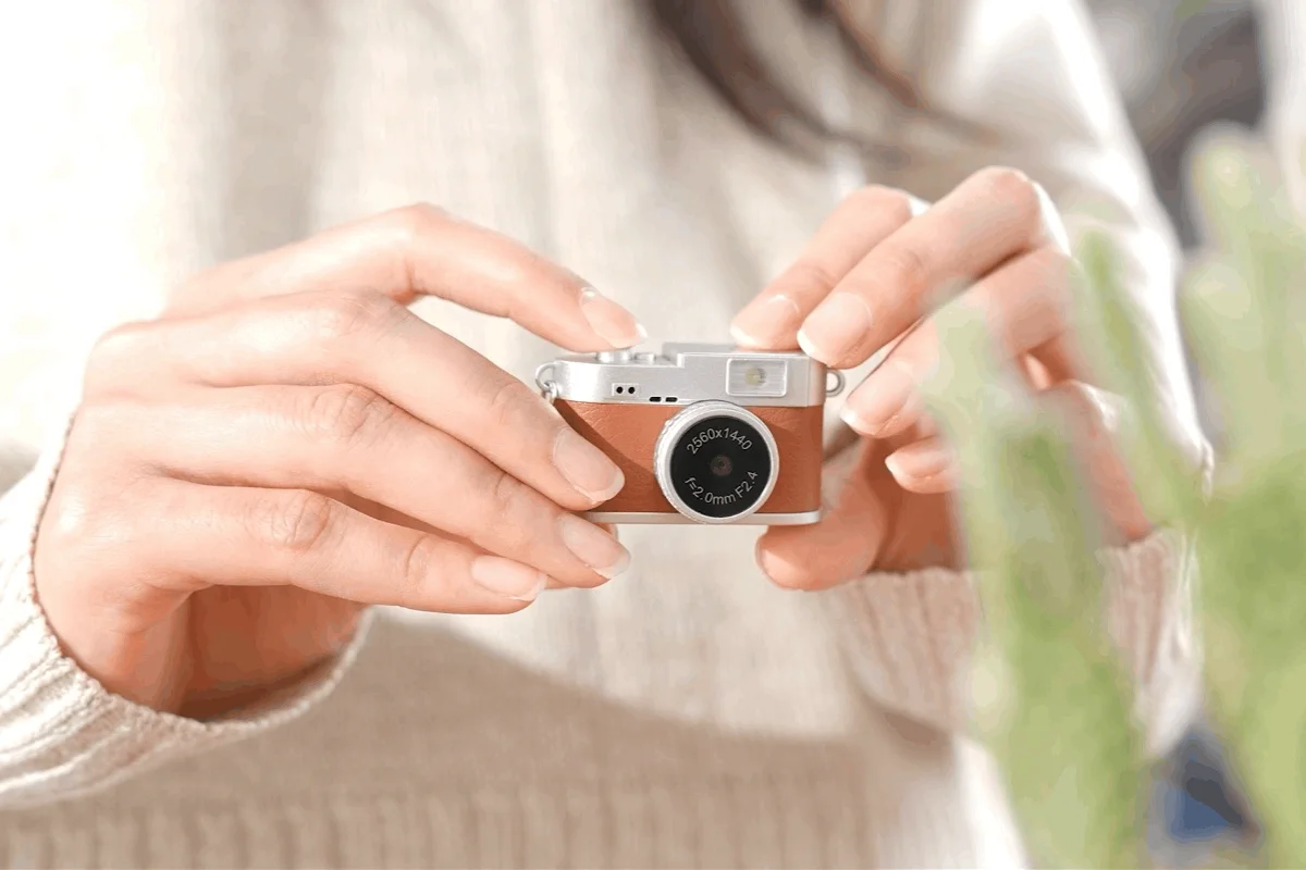 女性がレトロなミニカメラを両手で持っている画像