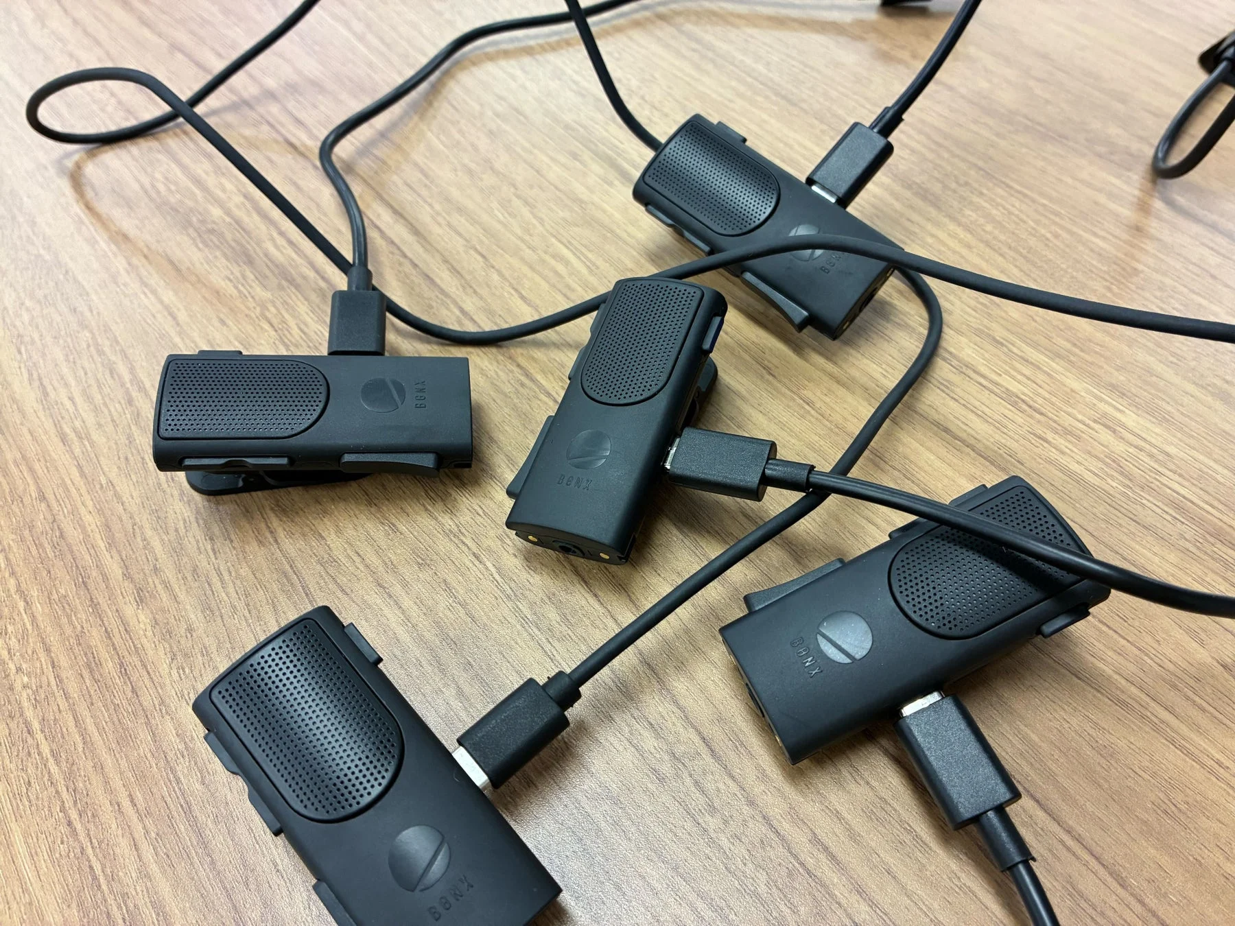 複数の黒い電子デバイスがUSB-Cケーブルで接続され、木製のテーブルに置かれています。