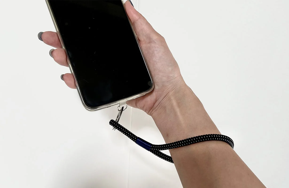 スマートフォンにリストストラップを取り付け、手首に通している様子