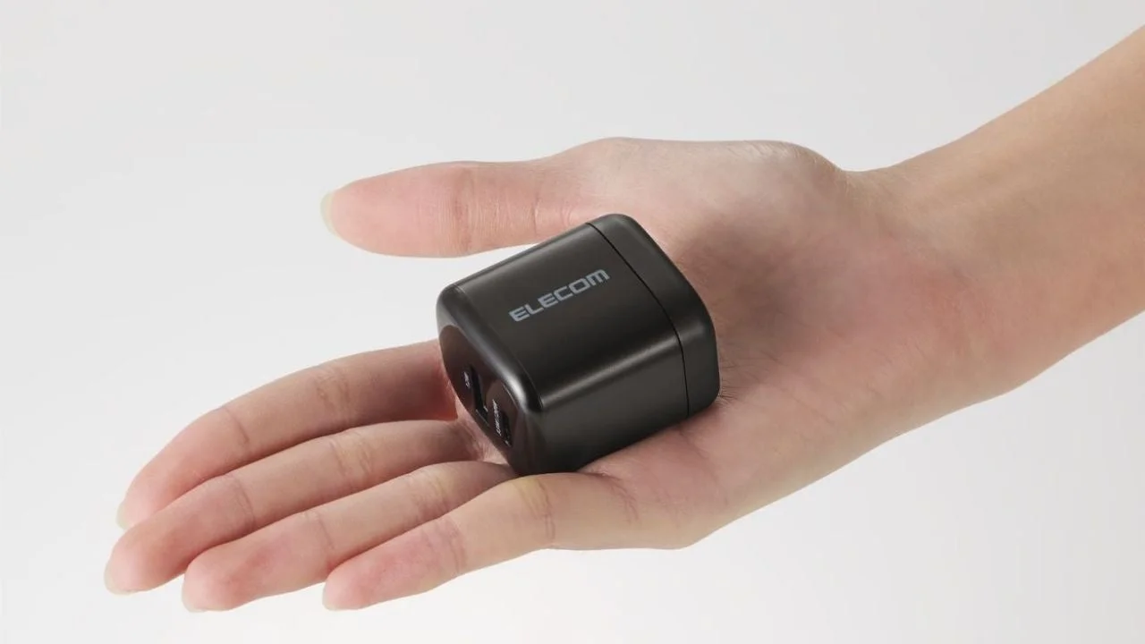 手のひらに収まるサイズの黒いELECOM製充電器またはアダプターが写っています。そのコンパクトさが強調されています。