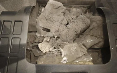 大量の灰色のほこりやゴミ、汚れたビニール袋などが詰まった容器の内部が写っています。