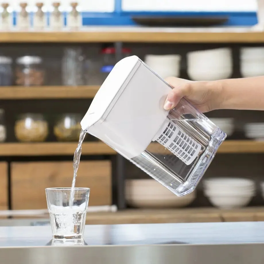 透明な浄水器ピッチャーから水がグラスに注がれている様子