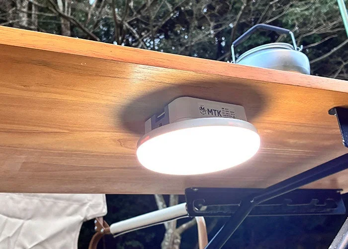 木製のテーブルの下に取り付けられた明るいLEDライトが、周囲を照らしている様子。