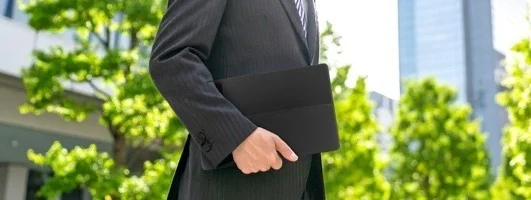 屋外でタブレットを手に歩くビジネスマン