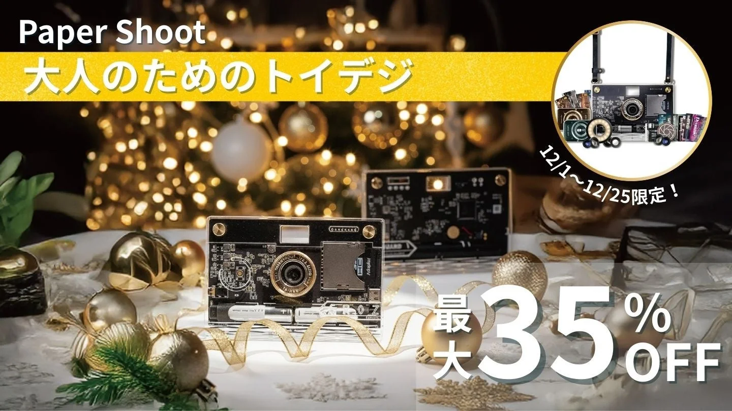 クリスマス装飾を背景に、Paper Shootのトイデジタルカメラを紹介する広告画像