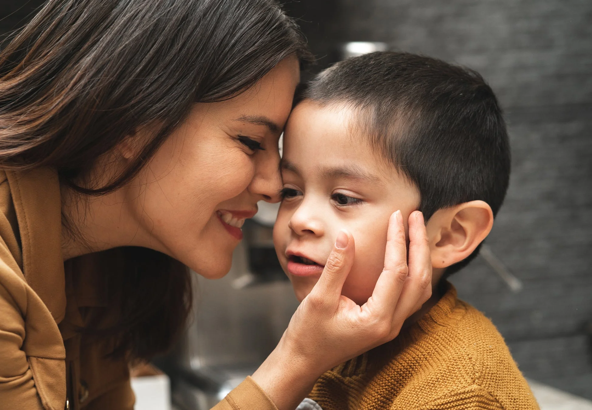 母親と幼い息子が額を寄せ合い、母親が優しく息子の頬に触れている心温まる瞬間