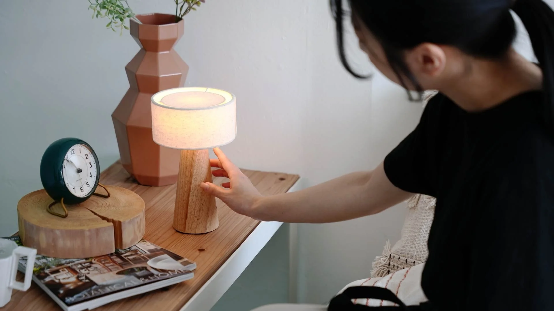 女性がベッドサイドテーブルに置かれたWottランプを操作
