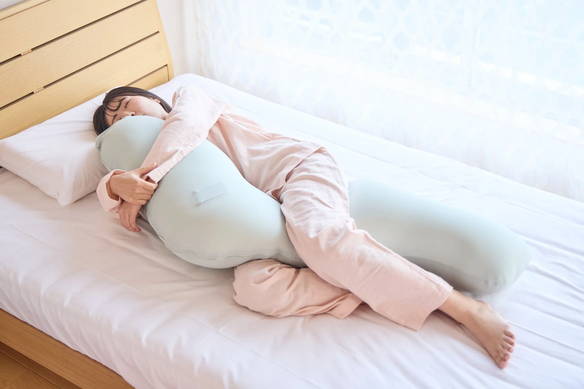 女性が抱き枕を抱きかかえて安らかに眠る