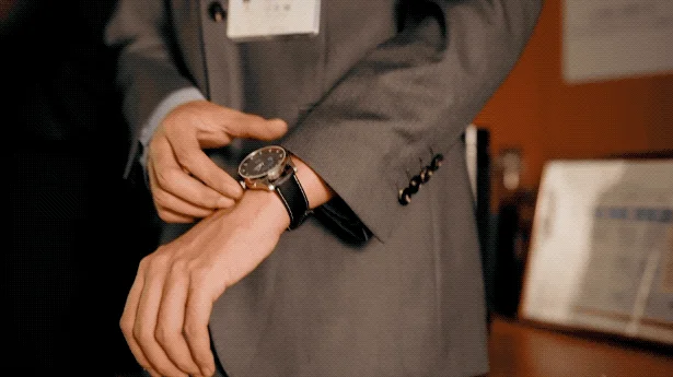 スーツ姿の男性が腕時計を調整している様子