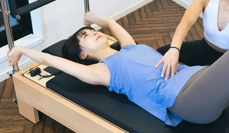 ピラティスリフォーマーでトレーニングする女性