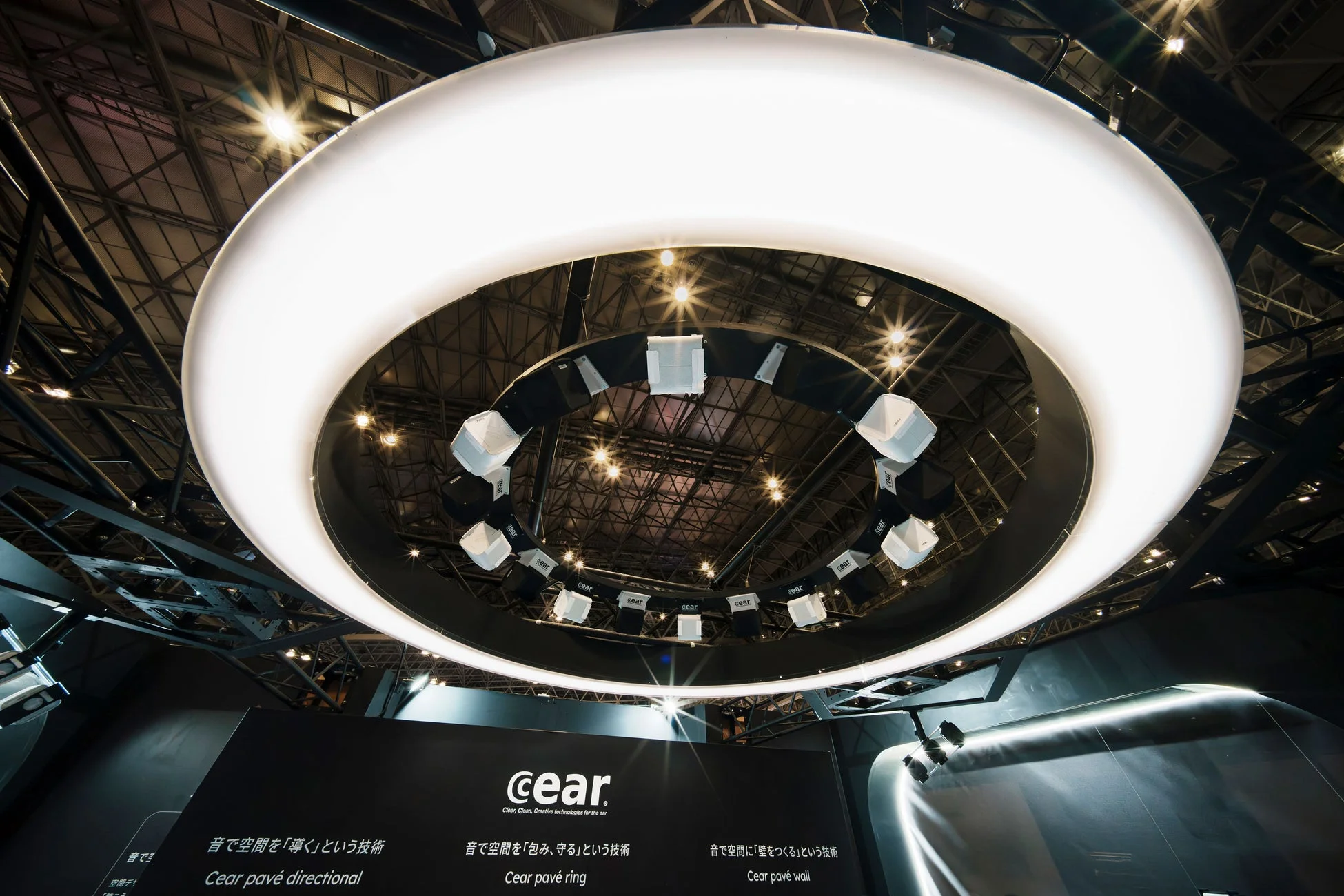 リング状の照明の下に多数の小型スピーカーが吊り下げられた展示