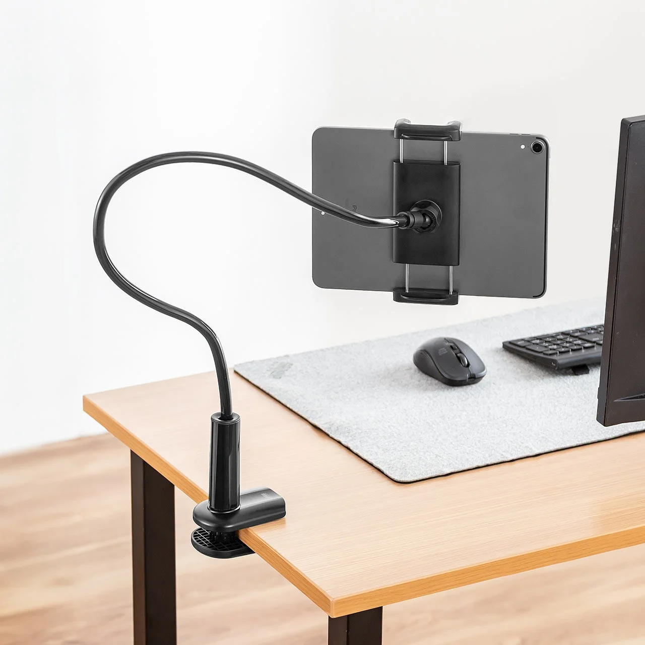 木製のデスクにクランプ式のフレキシブルアームスタンドでタブレットが固定