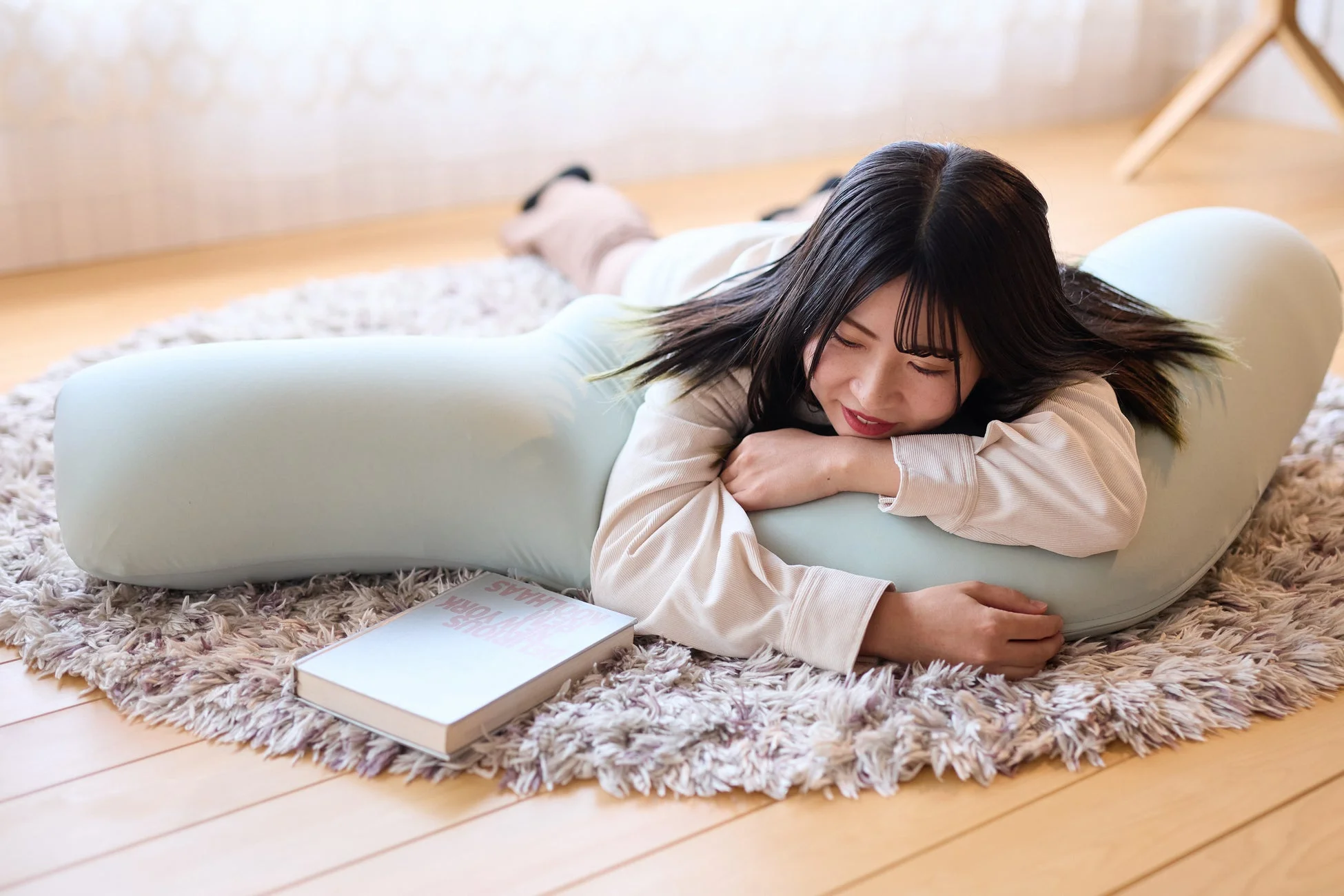 抱き枕にうつ伏せになりリラックスする女性