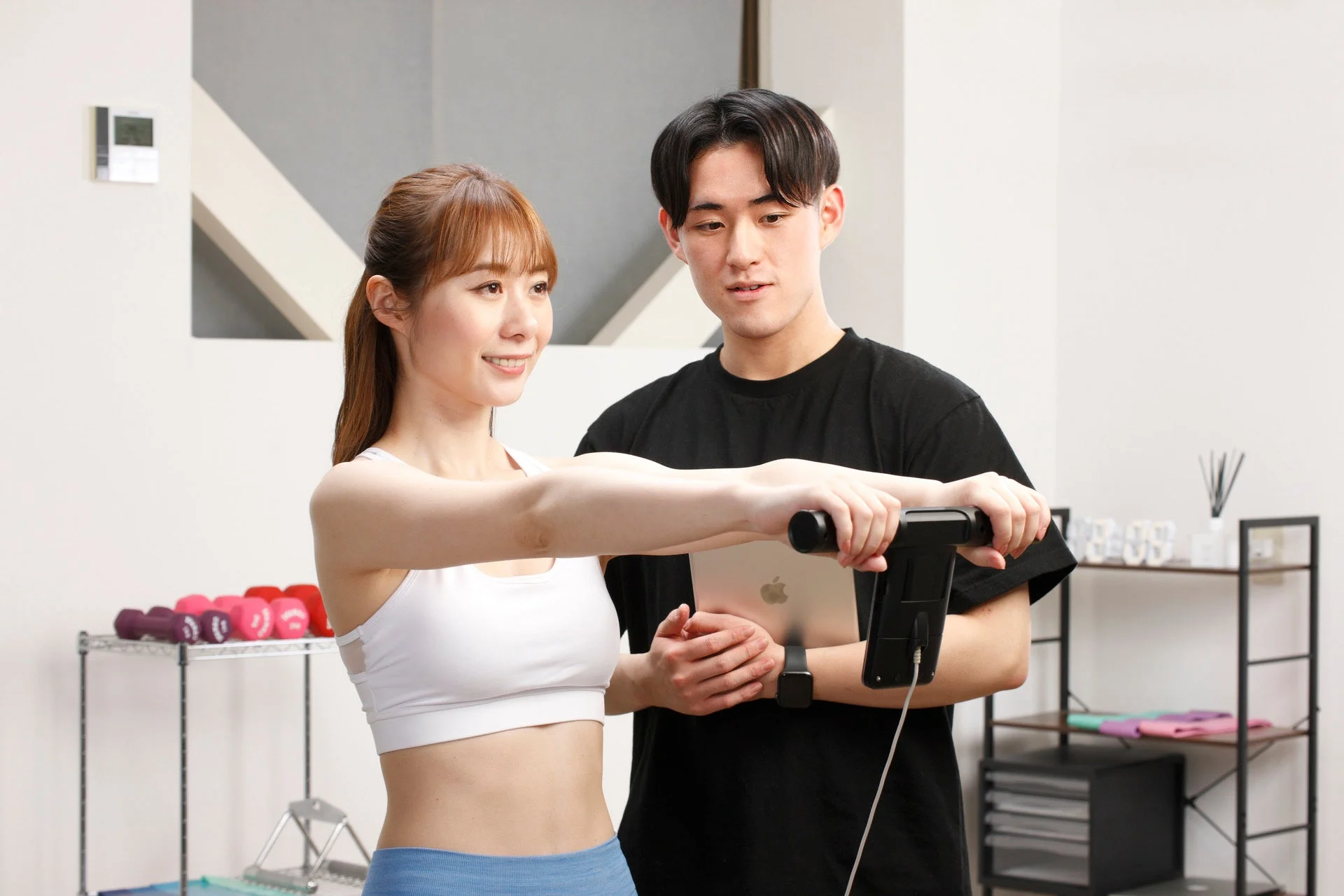 体組成計で体の状態を測定する女性とトレーナー