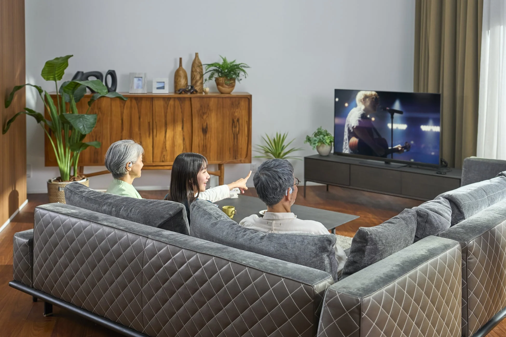 リビングでくつろぐ家族3人がソファに座ってテレビを見ているシーン