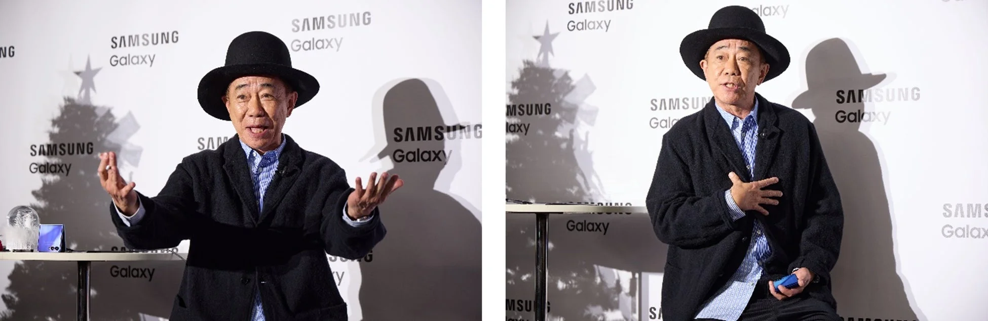 黒いハットとコートを着た男性が、SAMSUNG Galaxyのロゴが背景にある場所で話している様子。