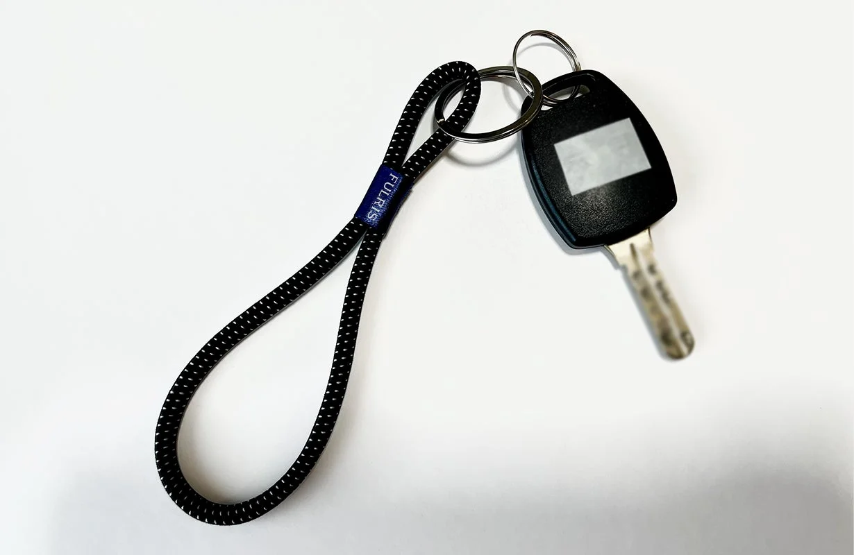 白い背景に置かれた、黒いストラップ付きの車の鍵