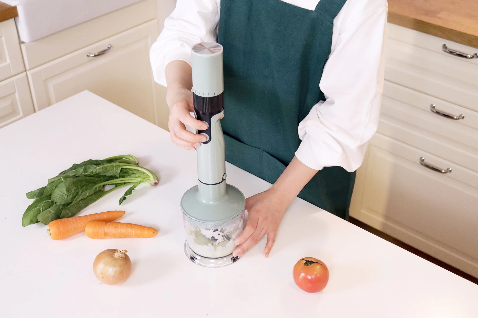 キッチンでハンドブレンダーを使う女性