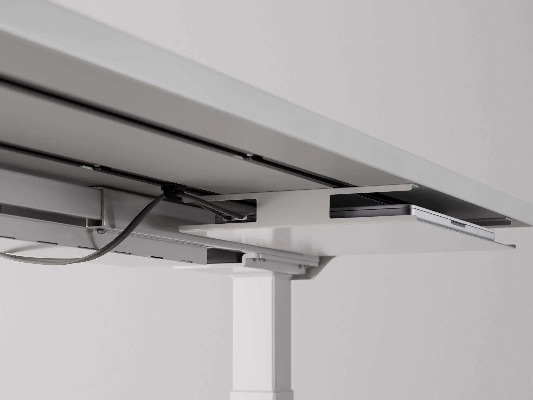 デスクの天板裏に整理されたケーブルとノートPC