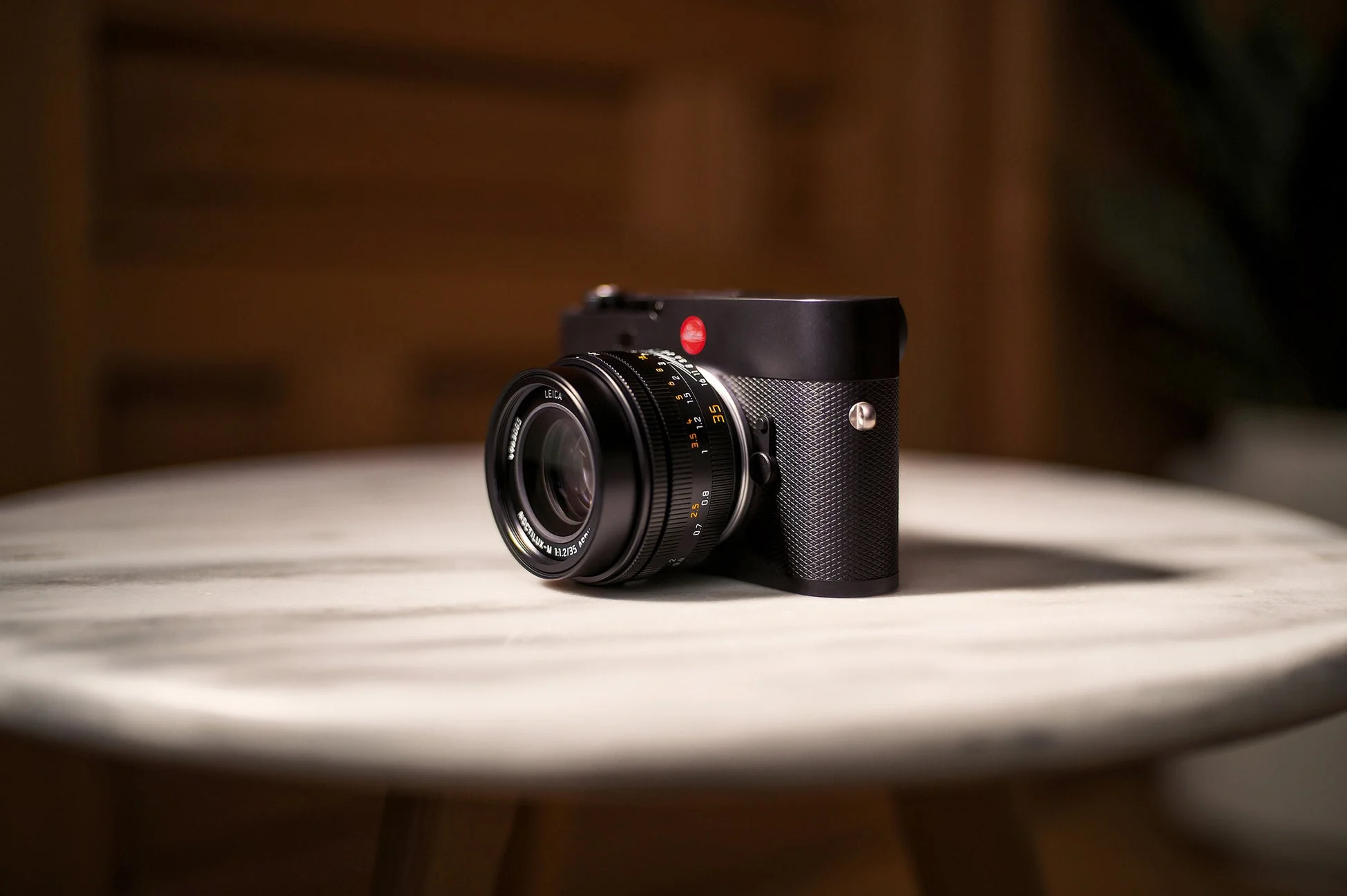 大理石調の丸いテーブルに置かれた黒いライカのデジタルカメラ