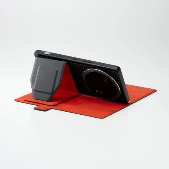 大きなカメラモジュールを持つ黒いスマートフォンが、内側が鮮やかな赤色の保護ケースで立てられた状態