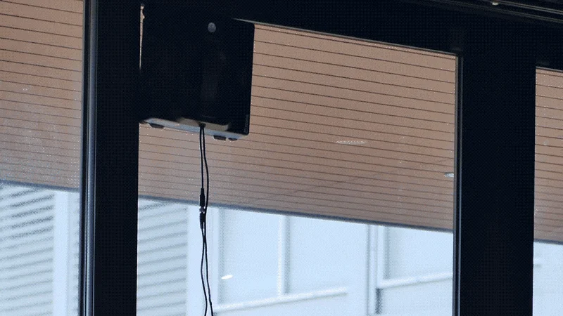 窓に吸着して自動で窓を掃除する黒いロボット