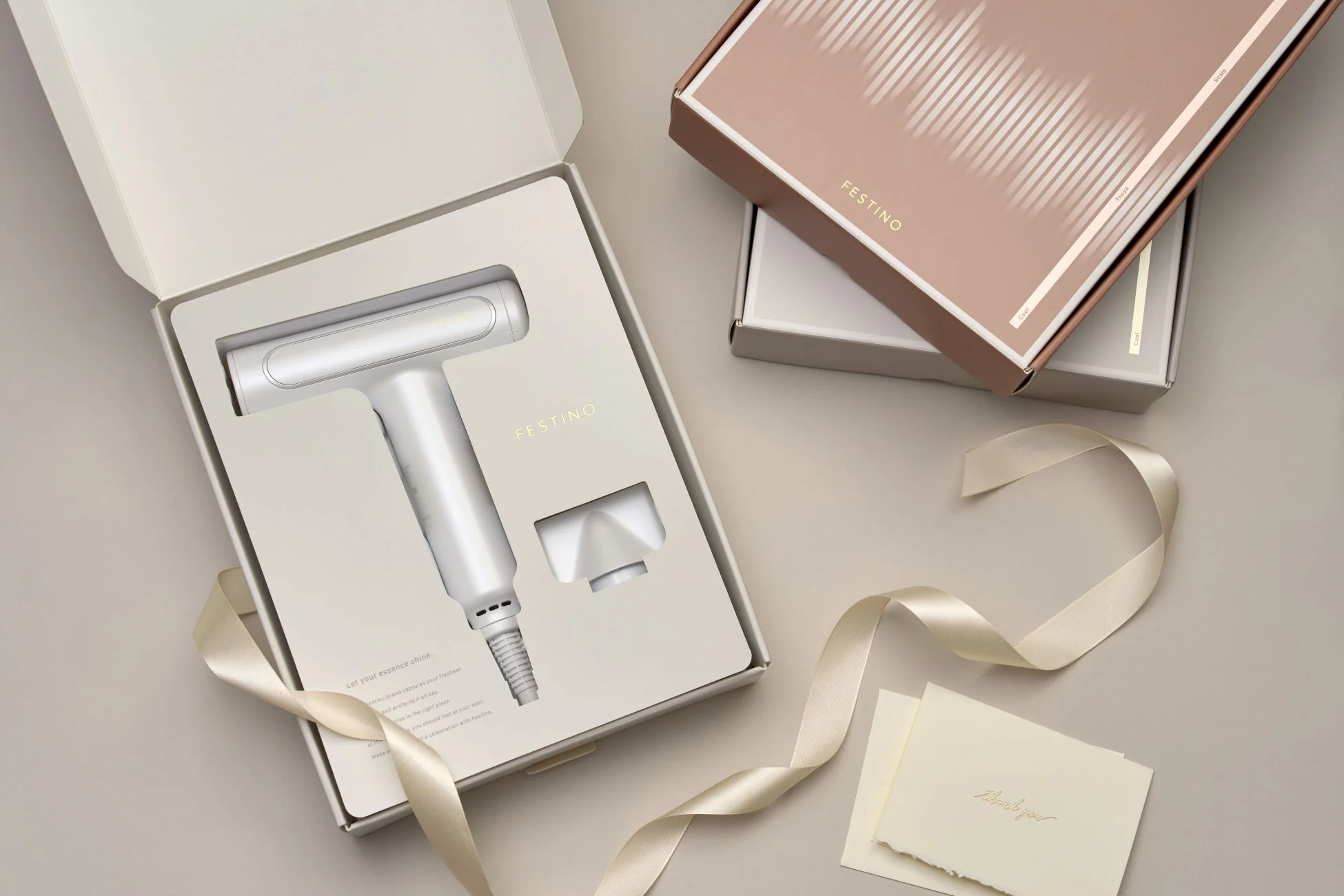 FESTINOブランドの美容家電（ヘアドライヤー）が白い箱に収められ、リボンとサンキューカードが添えられています。