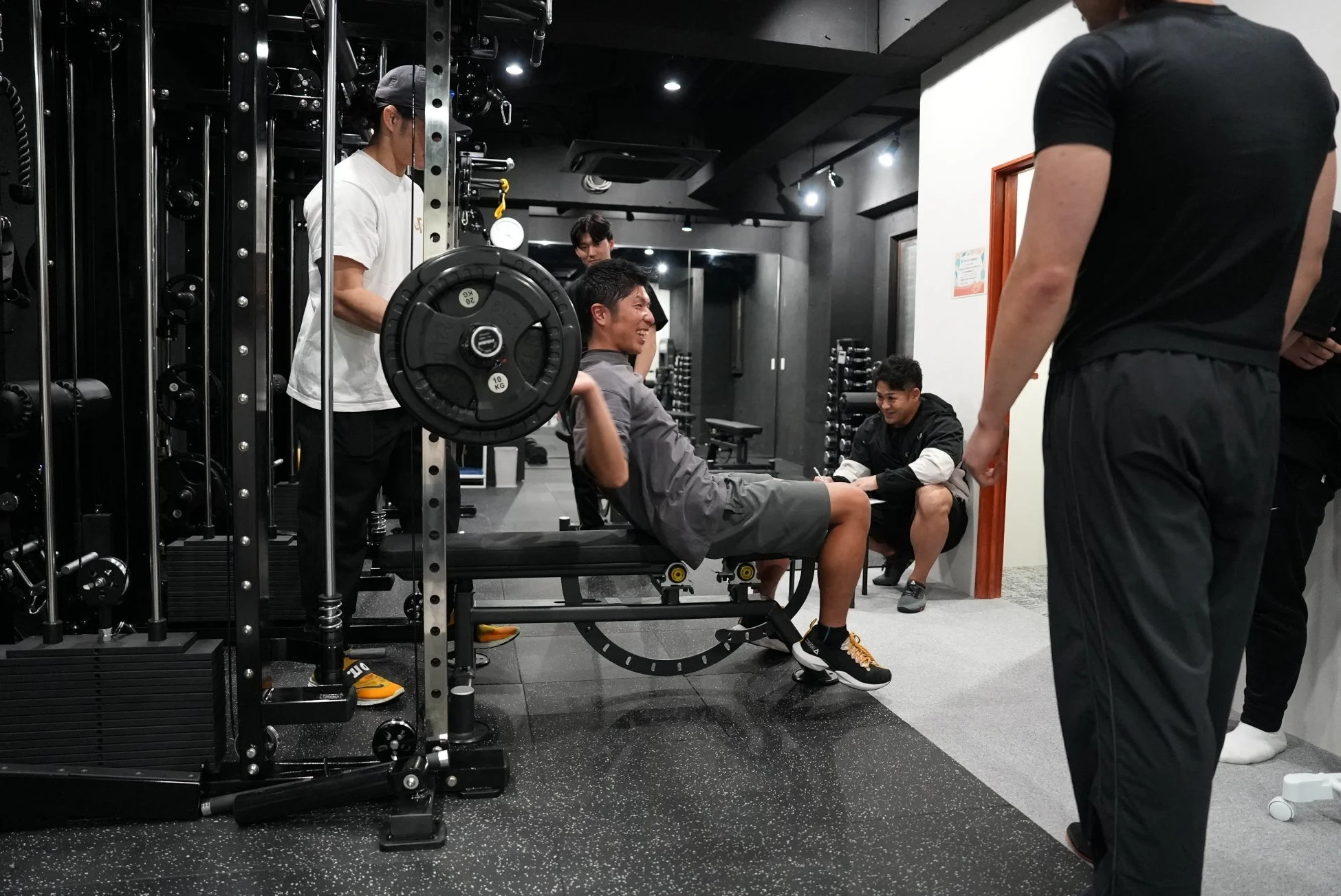 ジムでバーベルを担いでトレーニングする男性たち