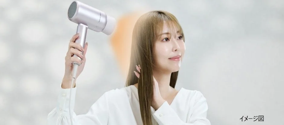 女性がドライヤーで髪を乾かしている様子