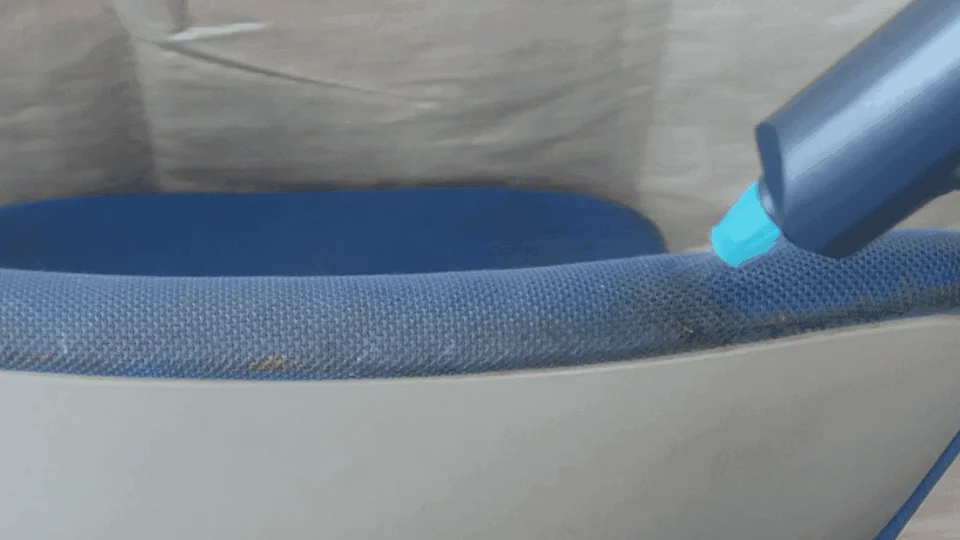 青い布張りの椅子の縁に付着した汚れを、青いクリーニングツールで掃除している様子